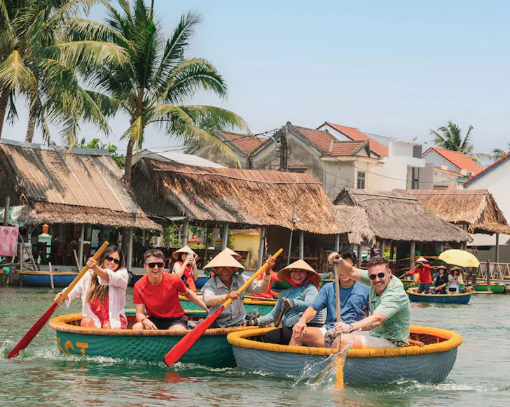 A group of people paddle in small boats in a river.