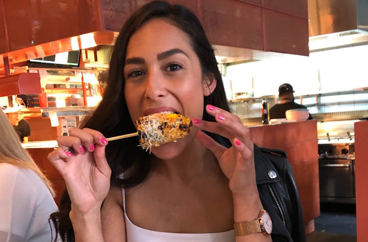 Person eating corn on a skewer