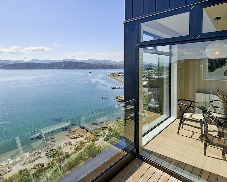A peek from the balcony into the living area of the Harbour View Home shows off a marble countertop, stylish seating, and incredible sea views