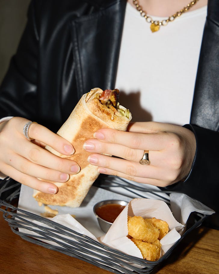 A woman holds a burrito. 