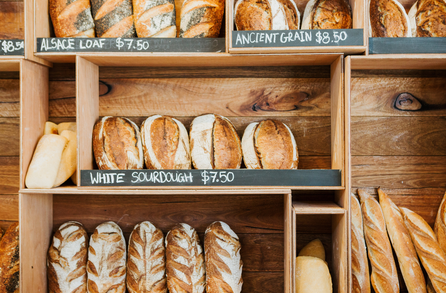 A wall of timber shelves filled with freshly baked bread at a Sunshine Coast bakery.