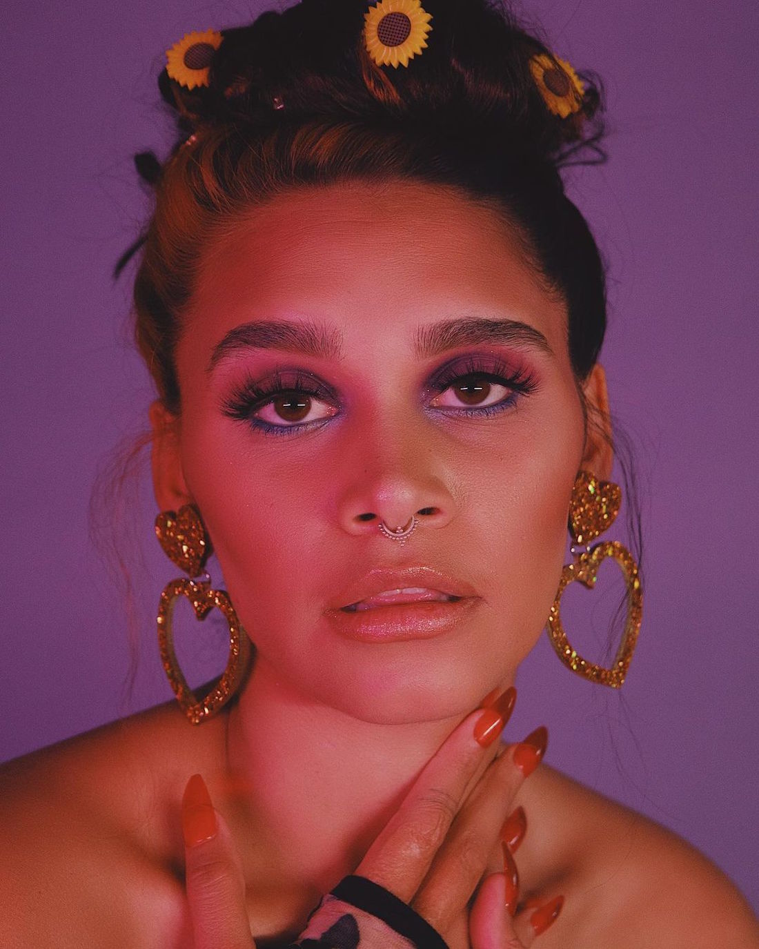 A woman gazes into the camera with her bold earrings and eye shadow glittering.