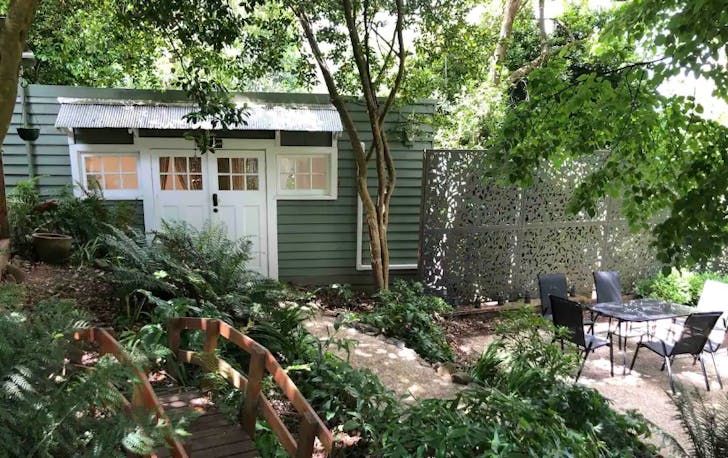 A garden with a small cottage in the background, a best Dandenong Ranges Airbnb.