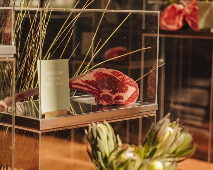 A piece of Tomahawk Steak on display in a glass cabinet.