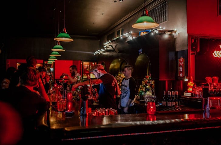 A busy cbd bar with green lamps and bartenders.