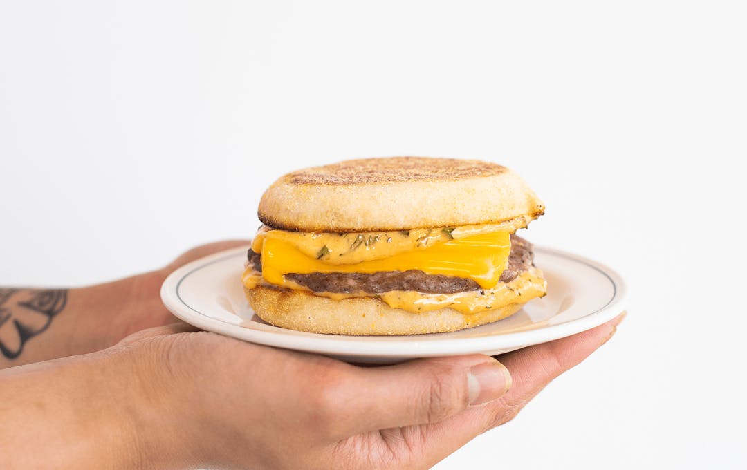 A person holding a cheesy sausage egg muffin.