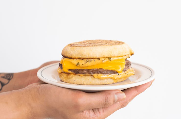 A person holding a cheesy sausage egg muffin.