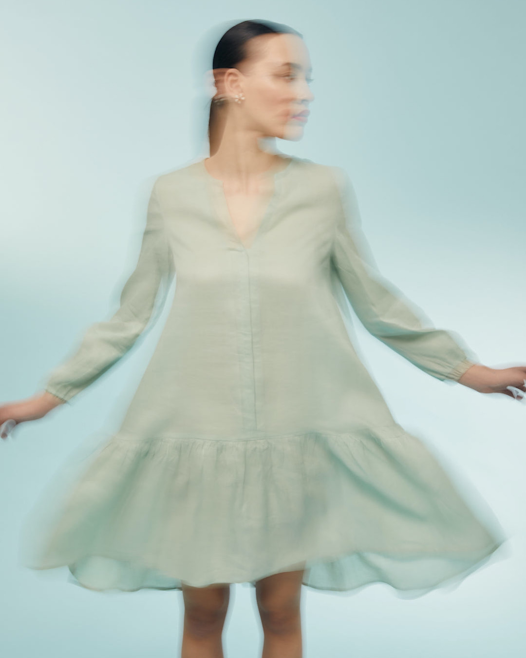 Woman mid-spin in a seafoam linen dress.