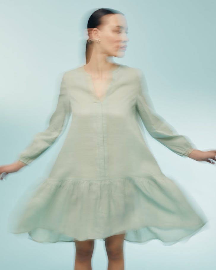 Woman mid-spin in a seafoam linen dress.