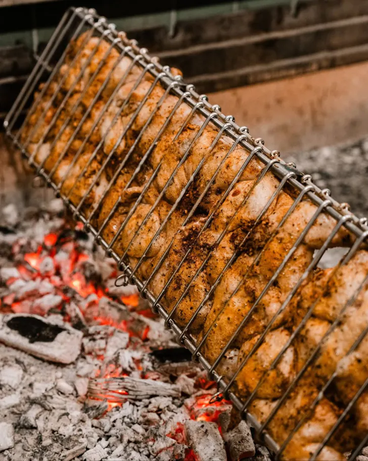 A hot barbecue cooks a row of chickens at Henrietta Chicken
