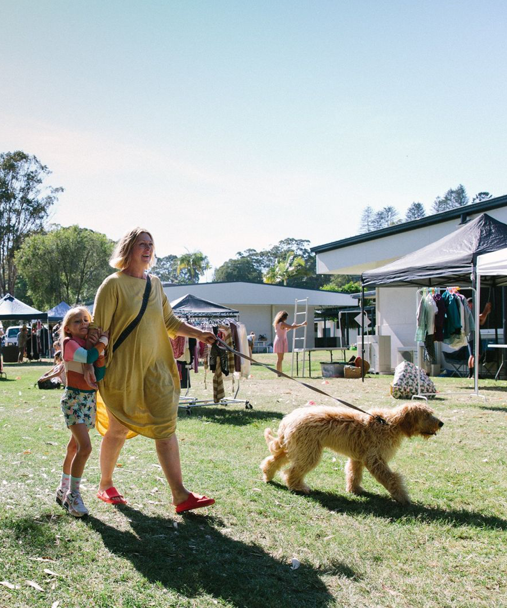 a woman and child walking a dog at a market