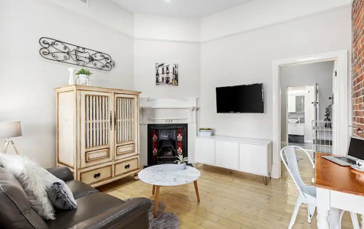 A clean white-walled accommodation in geelong with a leather couch.