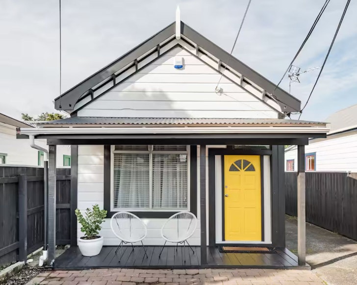 The exterior with its yellow door at Heritage Listed Cottage one of the best Wellington Airbnbs