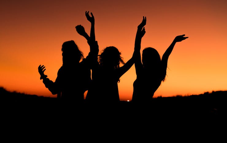 The silhouettes of three women against a sunset