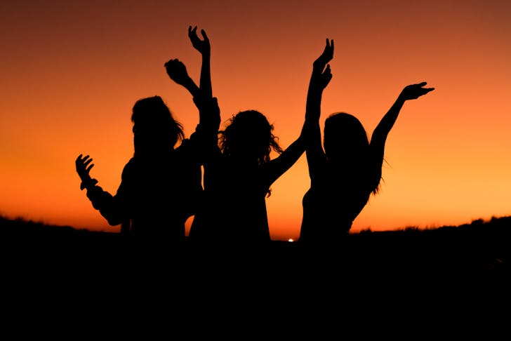 The silhouettes of three women against a sunset