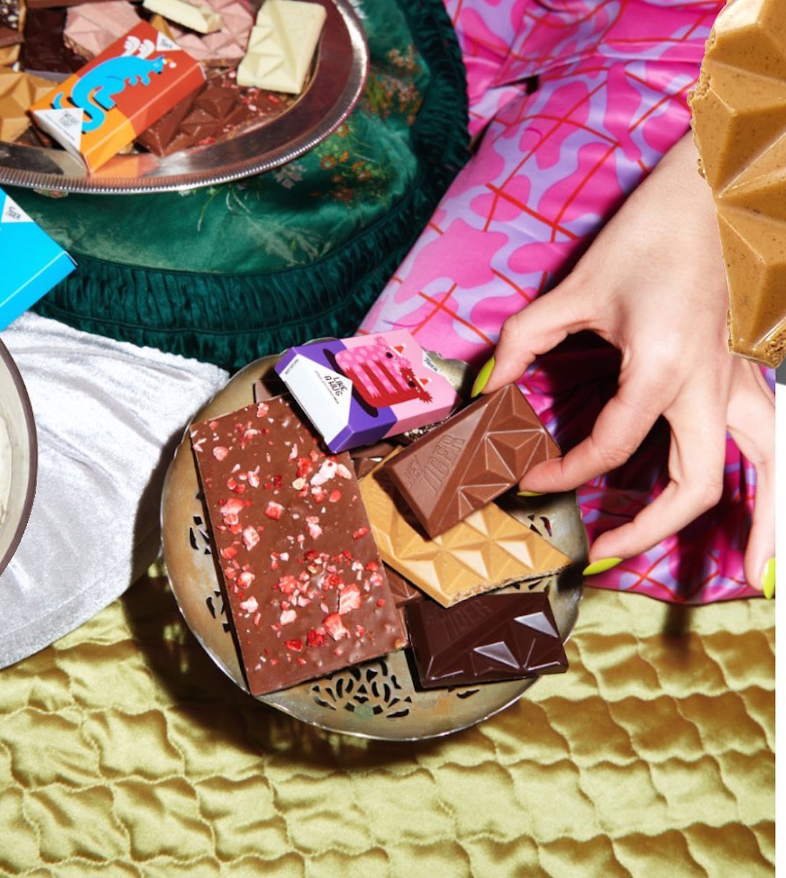 A hand reaches for a full plate of delicious Hey Tiger Co chocolate.