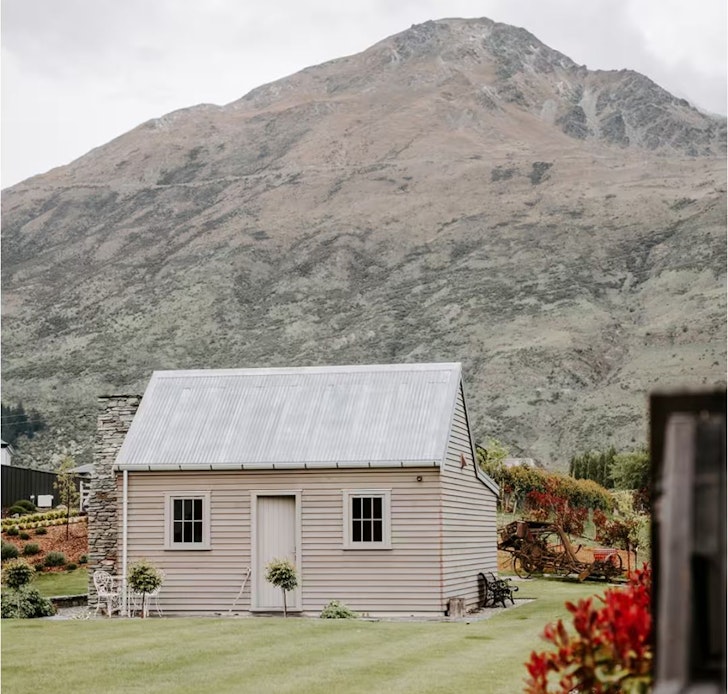 An exterior view of Hicks Cottage with a mountain backdrop near Queenstown, New Zealand