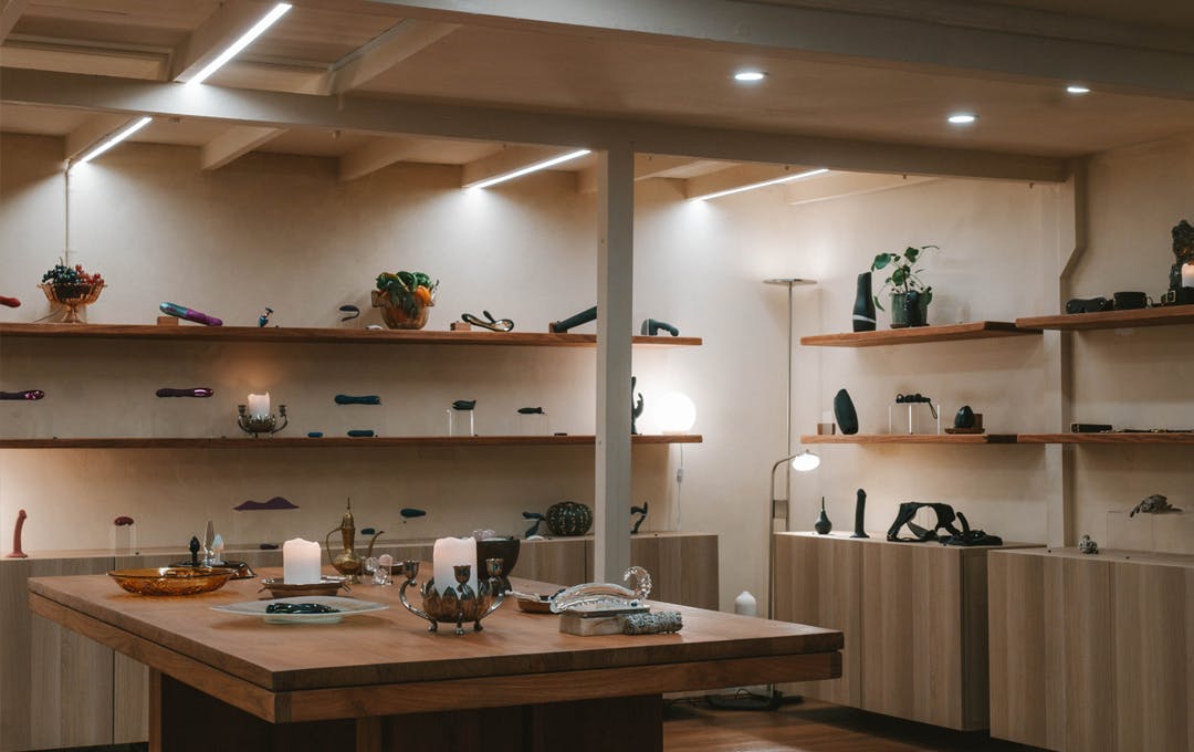 A dim lit shop with wood shelving and sex toys. 