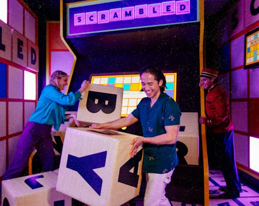 Three people playing in a purple-lit room. 