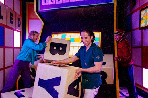 Three people playing in a purple-lit room.
