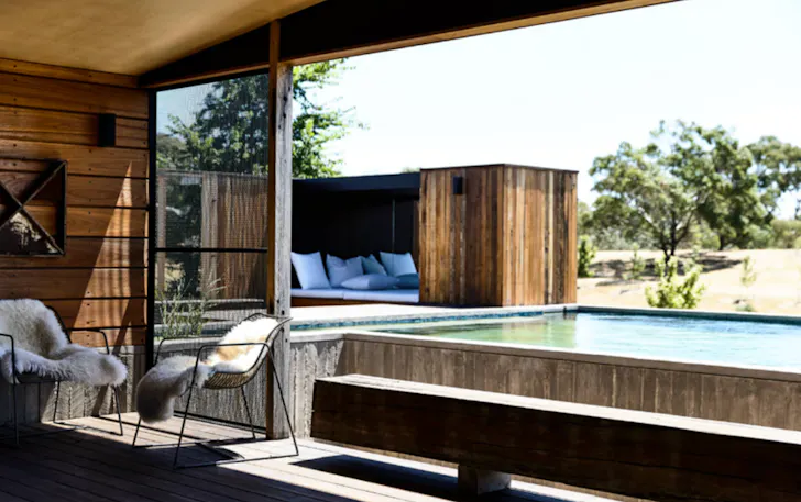 Floor-to-ceiling bi-fold doors are fully open, opening to a romantic pool set in this romantic getaways victoria stay.