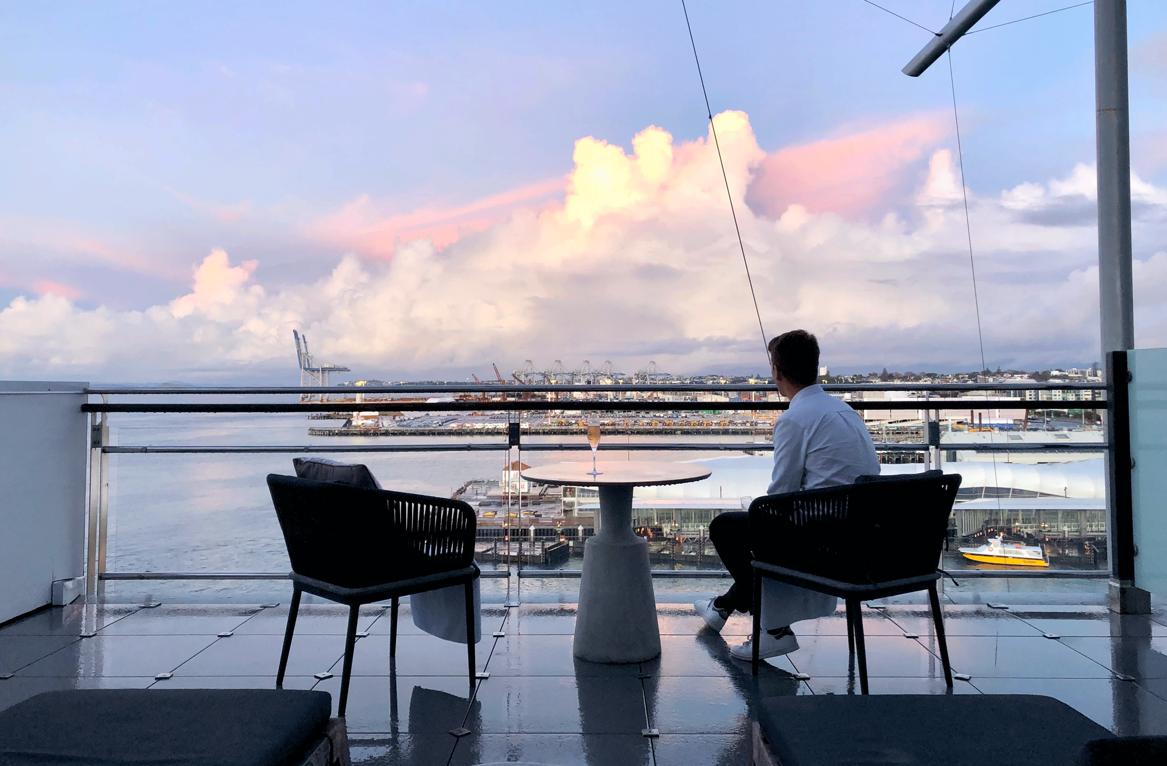 Man sits on the balcony at sunset at the Hilton Auckland