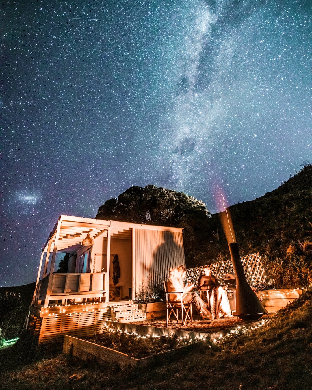 Two people huddle under a blanket at a tiny home under the stars.