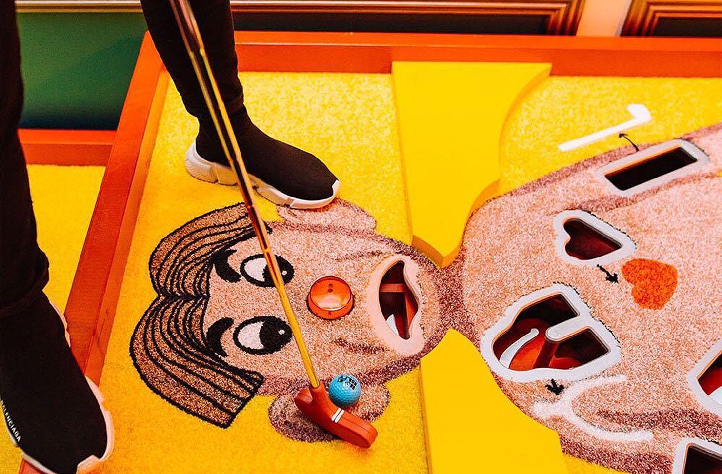 A person putts a ball on an Operation man's face.