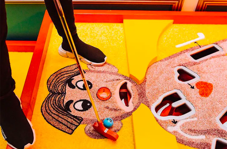 A person putts a ball on an Operation man's face.