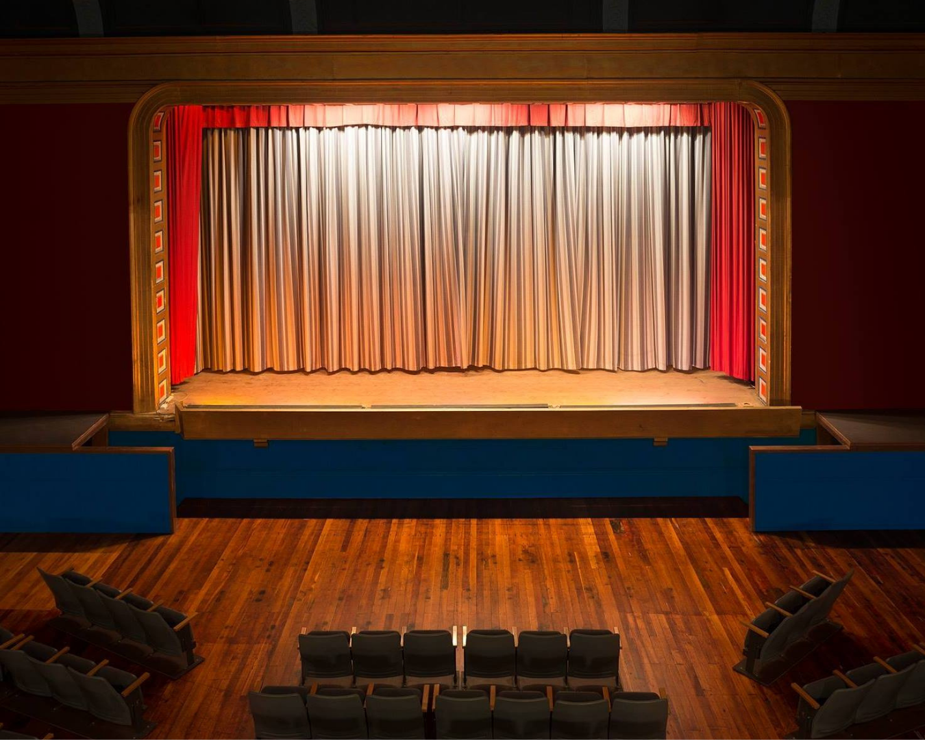 An empty theatre with curtains drawn and spotlight on stage