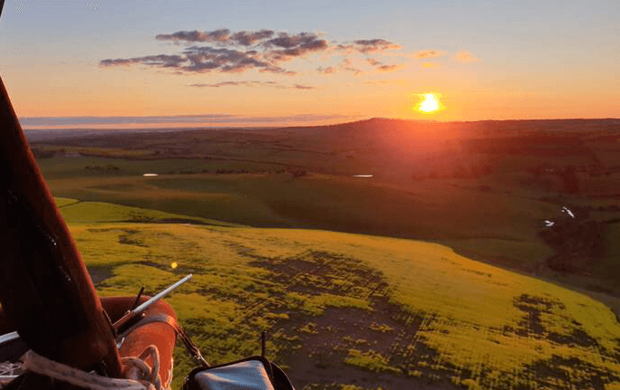 A POV-view of a hot air balloon experience in Geelong with large fields. 