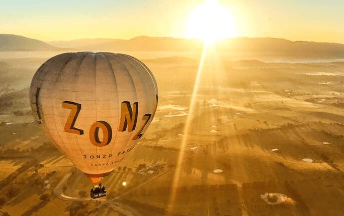 A hot air balloon at sunrise soaring high up. 