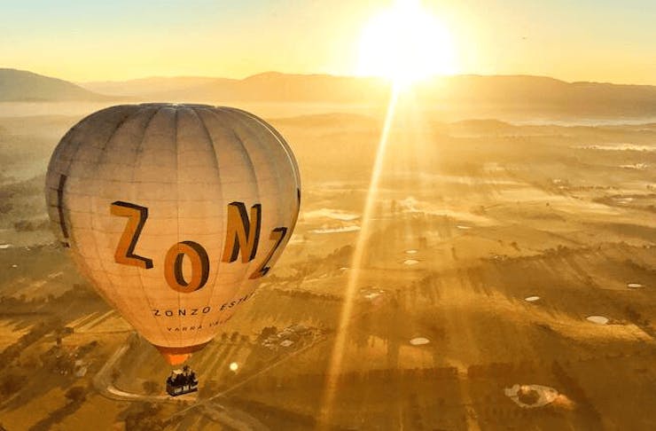 A hot air balloon at sunrise soaring high up. 