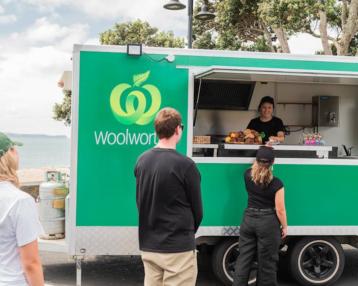 A green Woolworths food truck that's giving away hot cross buns. 