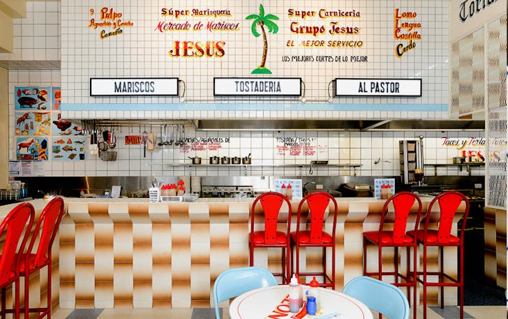 A counter with tiled bar and red stool chairs. 