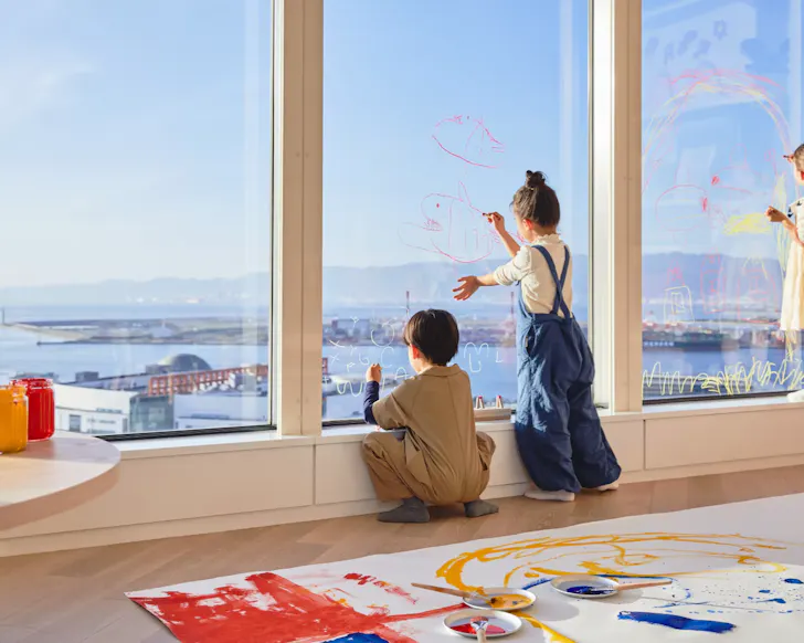 Kids use special crayons to draw on the glass windows overlooking the city at Risonare Osaka