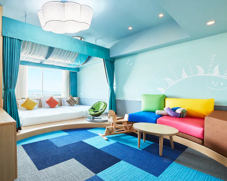 A colourful, bright blue room with a rocking horse and wall murals at Hotel Universal Port.