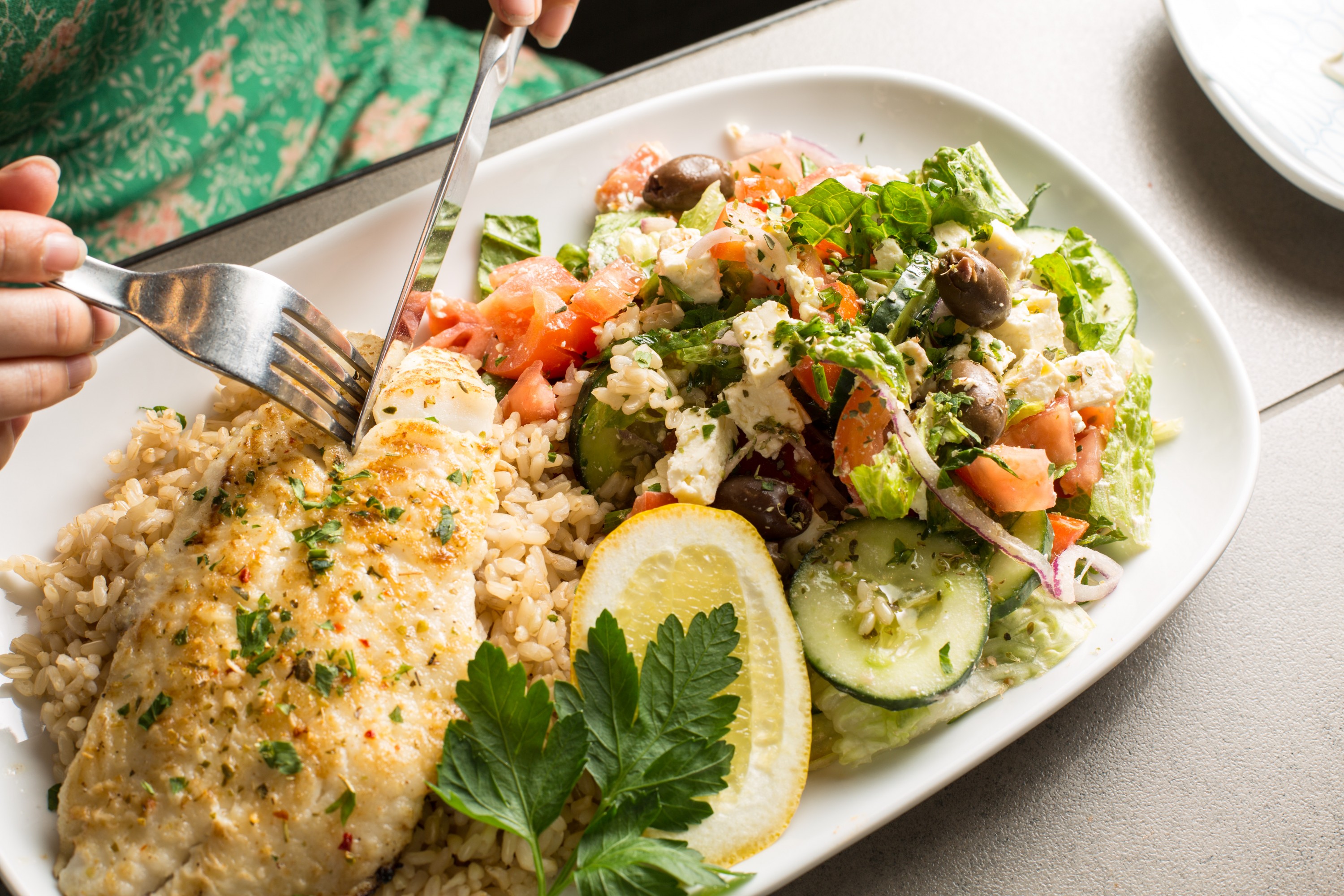 A person cutting into a piece of grilled fish at a fish and chips melbourne spot. 