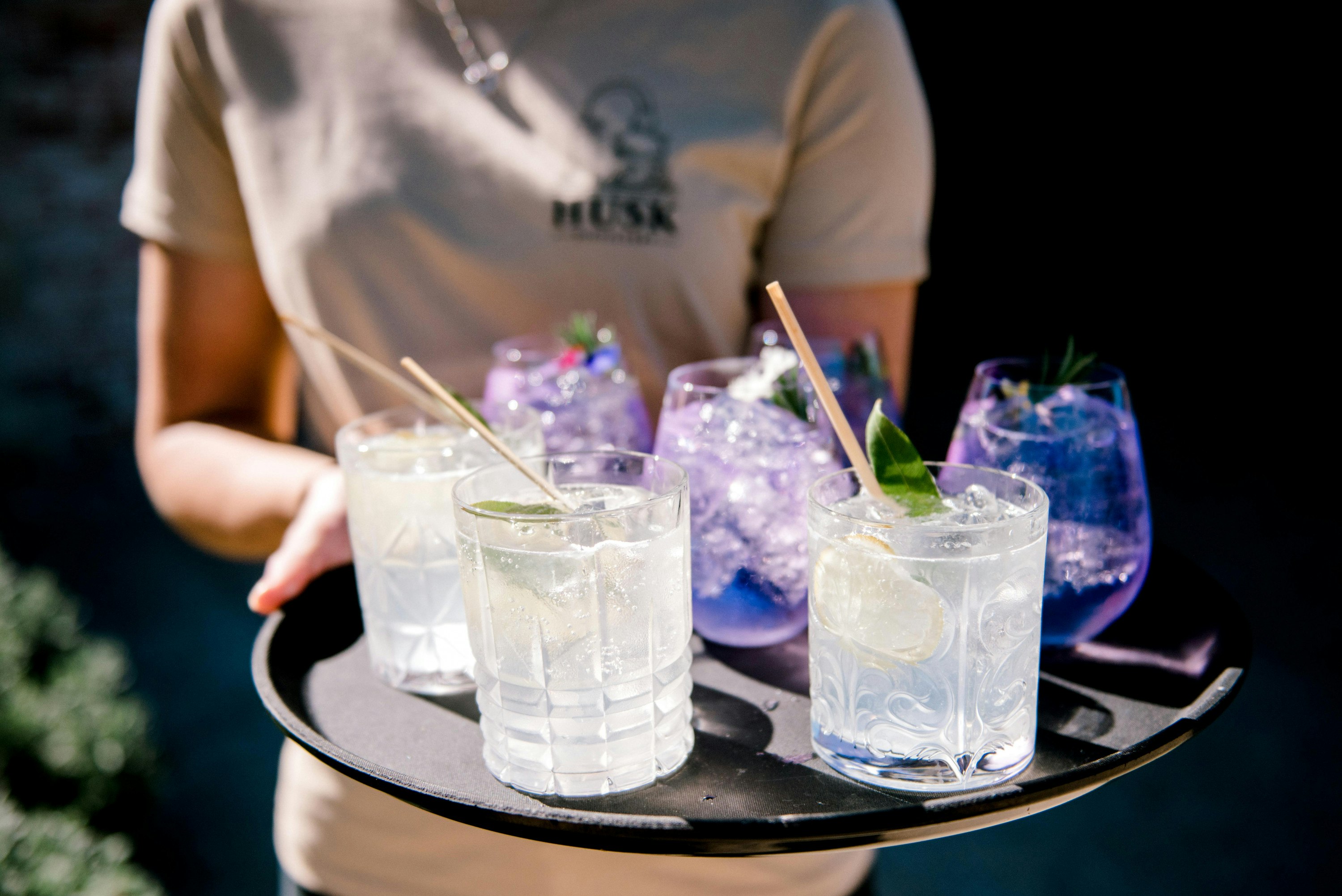someone holding a tray of cocktails