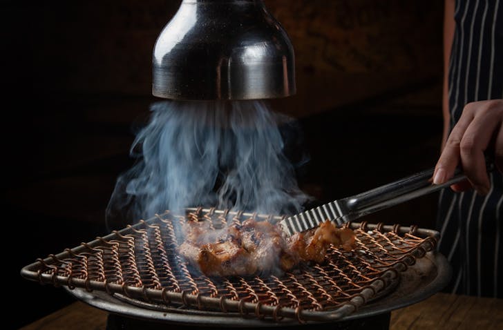 An extractor sucking up all the smoke from someone cooking meat on a Korean BBQ at one of the best Korean BBQ restaurants in Melbourne called Hwaro