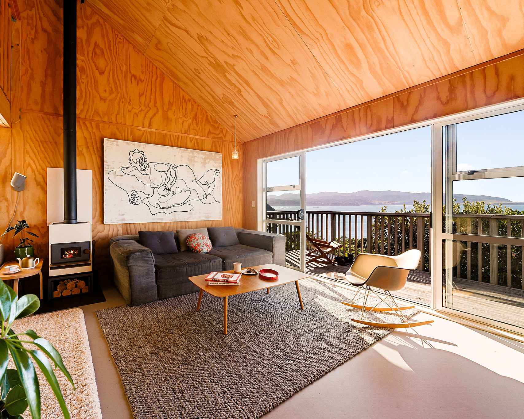 Warm wooden interiors of Hygge Hus retreat, with high ceilings, a fireplace, unique artworks and a large balcony overlooking the ocean.