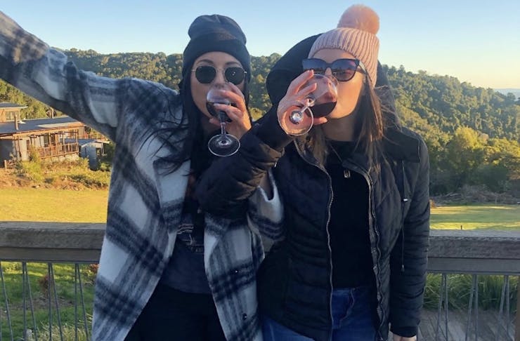 Two girls sip wine at a winery