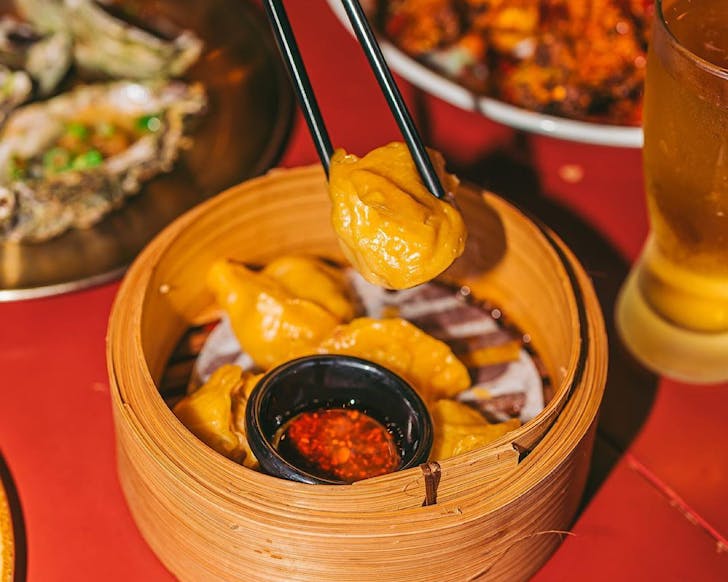 Chopsticks pick up a Mr hao dumpling from a steamer basket
