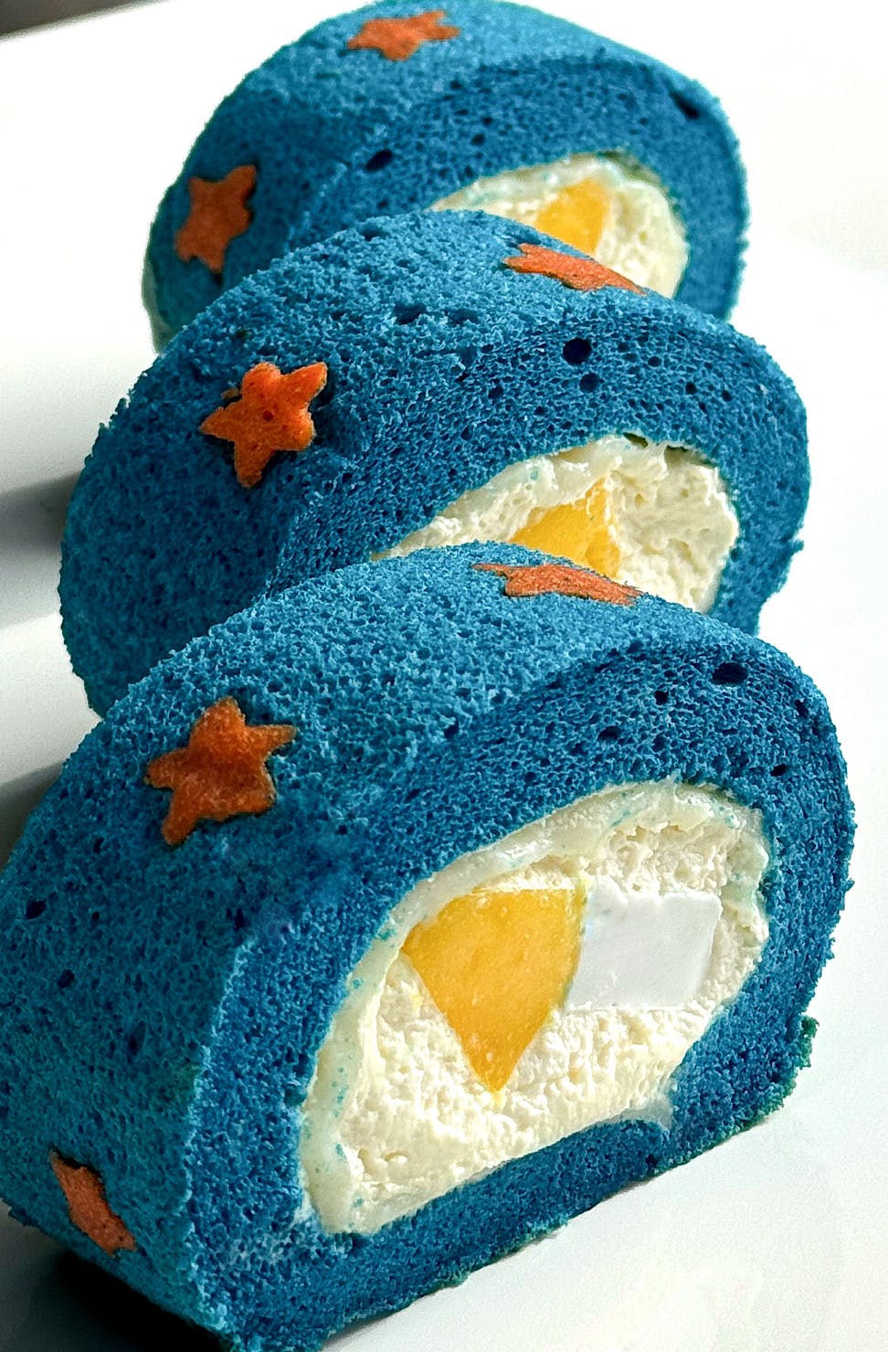 Three slices of blue-coloured mochi-stuffed swiss rolls by Fankery. 