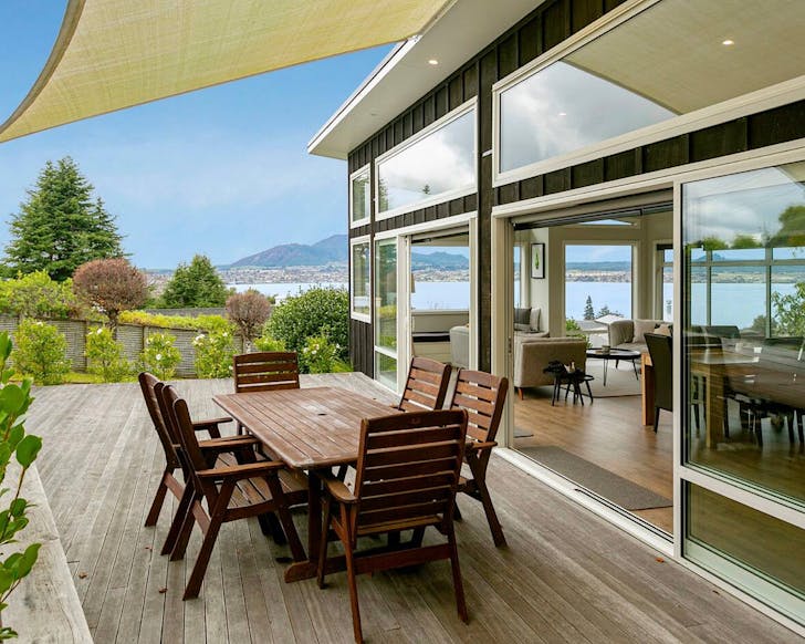 A nice deck area and weatherboard house with a fabulous view of a lake, town and mountains.