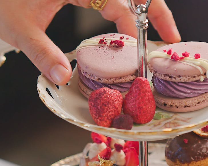 A hand reaches for Nanamâs ube macaron as part of their Filipino High Tea