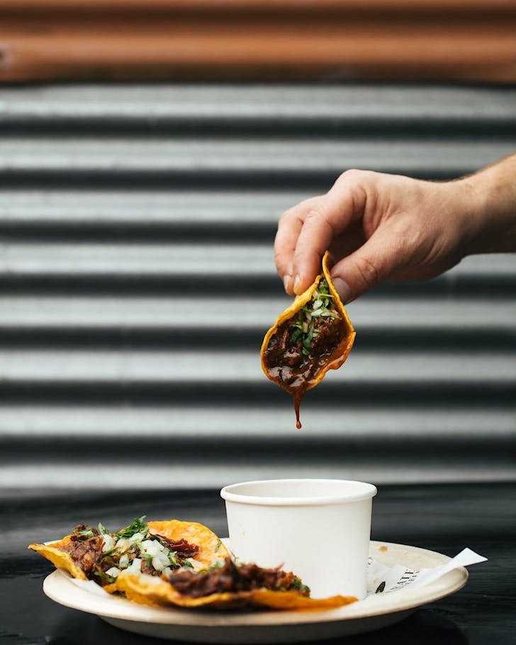 A hand dips a birria taco from Stone Oven (Photography by Emily Raftery)
