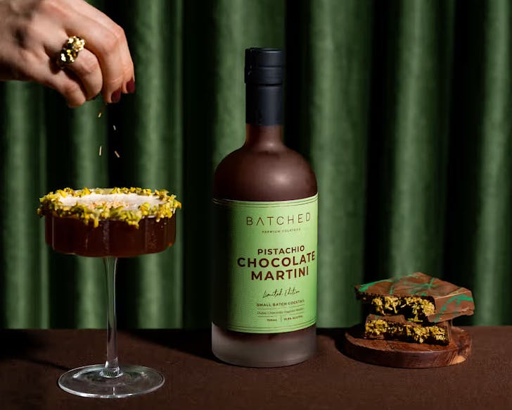 An elegant hand garnishes the new Batched Pistachio Chocolate Martini cocktail l