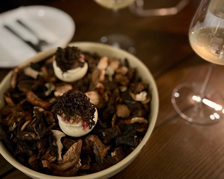 A bowl of truffle bao sits on dried porcini and mushrooms at The Wine Room