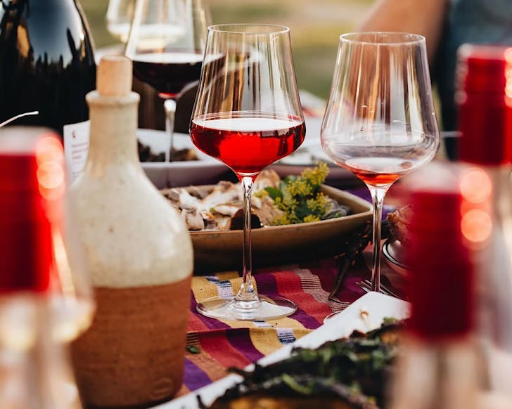 Huntress wines sit amongst a table adorned with sharing plates of food 